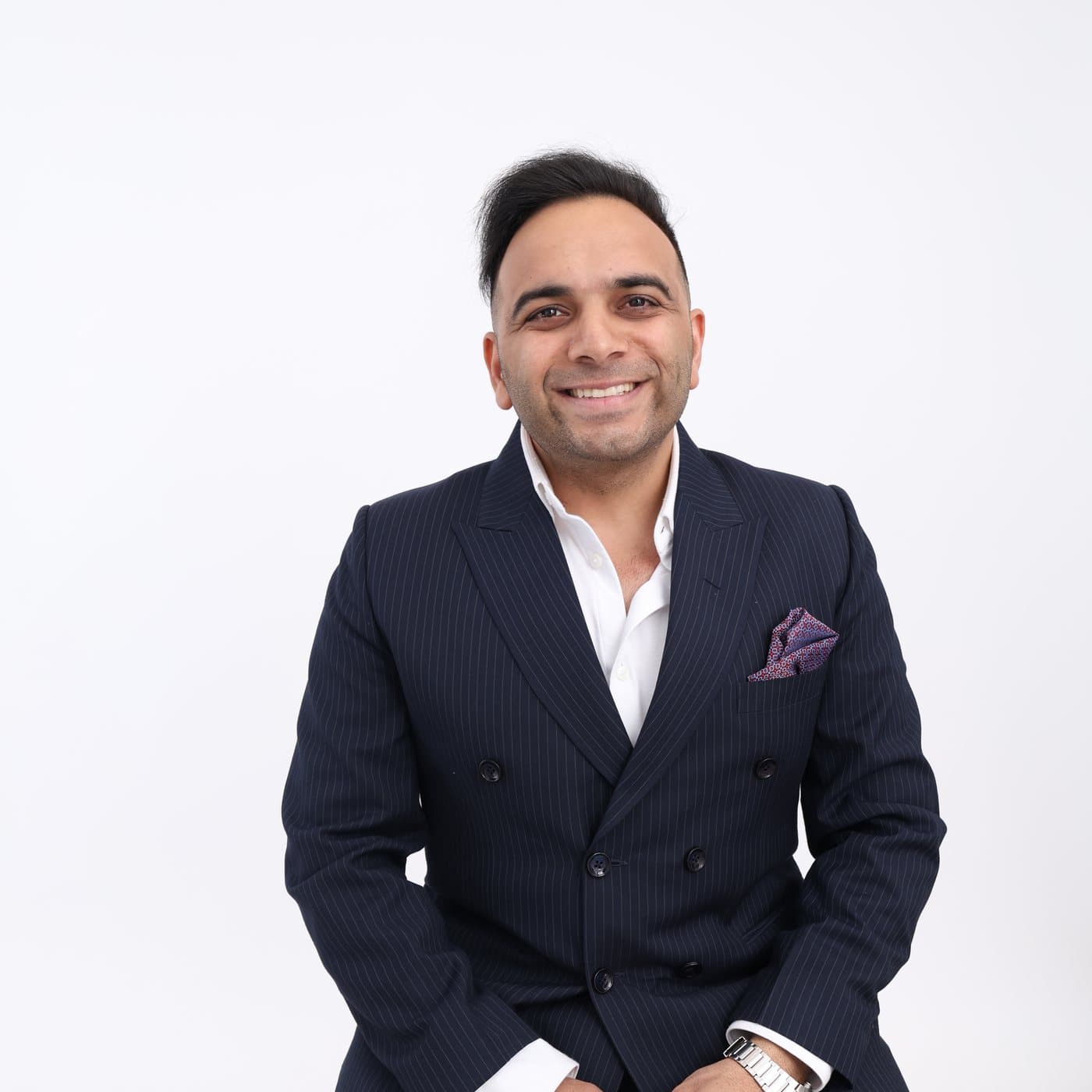 Bhavesh Khurana in a navy pinstripe suit against a plain white background.